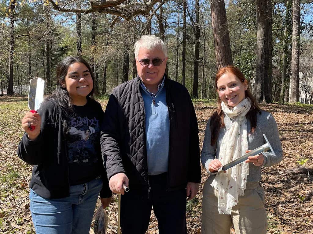 Students with Re:wild Your Campus Emory pose with grounds manager while collecting soil samples. 